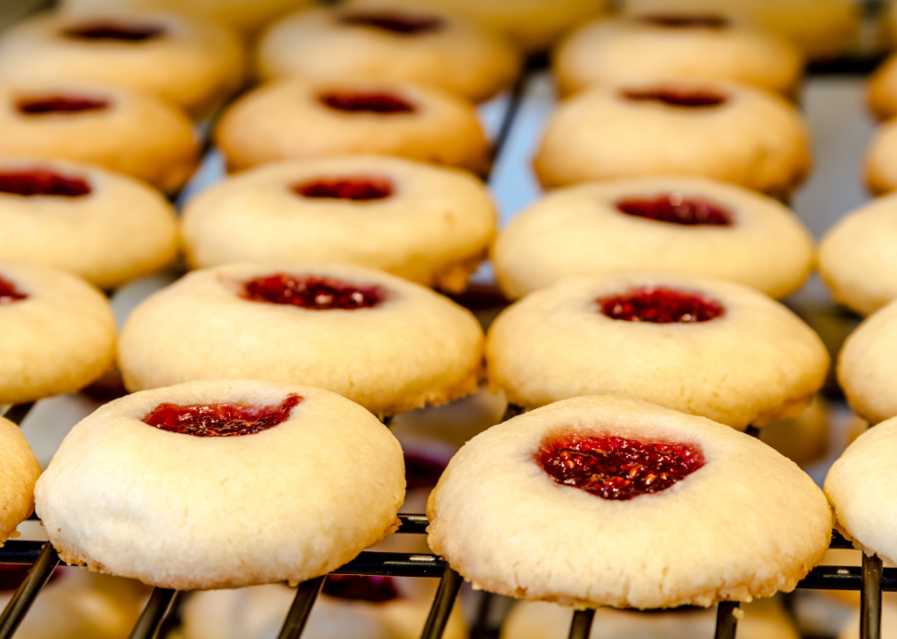 Little cookies with red filling in the center on a baking rack.