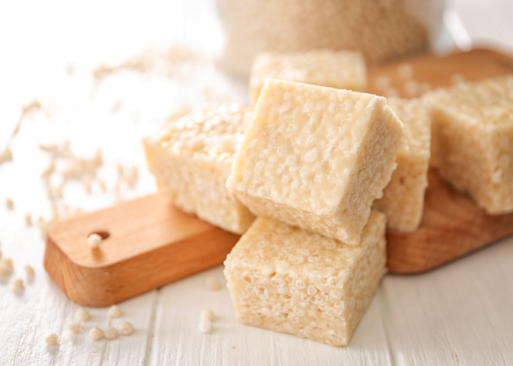 A stack of rice krispie treats on a wooden cutting board.