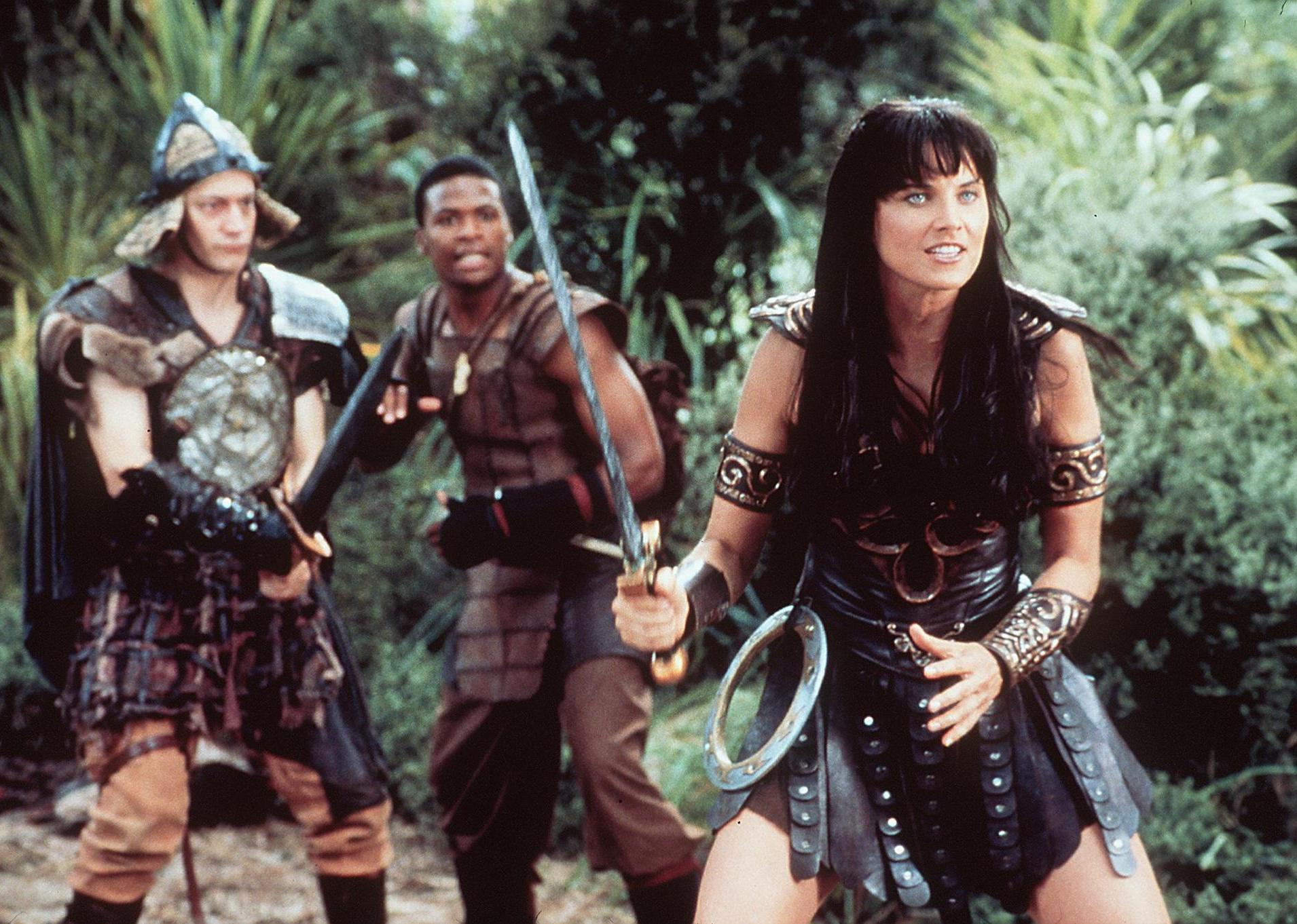 Lucy Lawless as Xena and other warriors engaged in battle with swords.