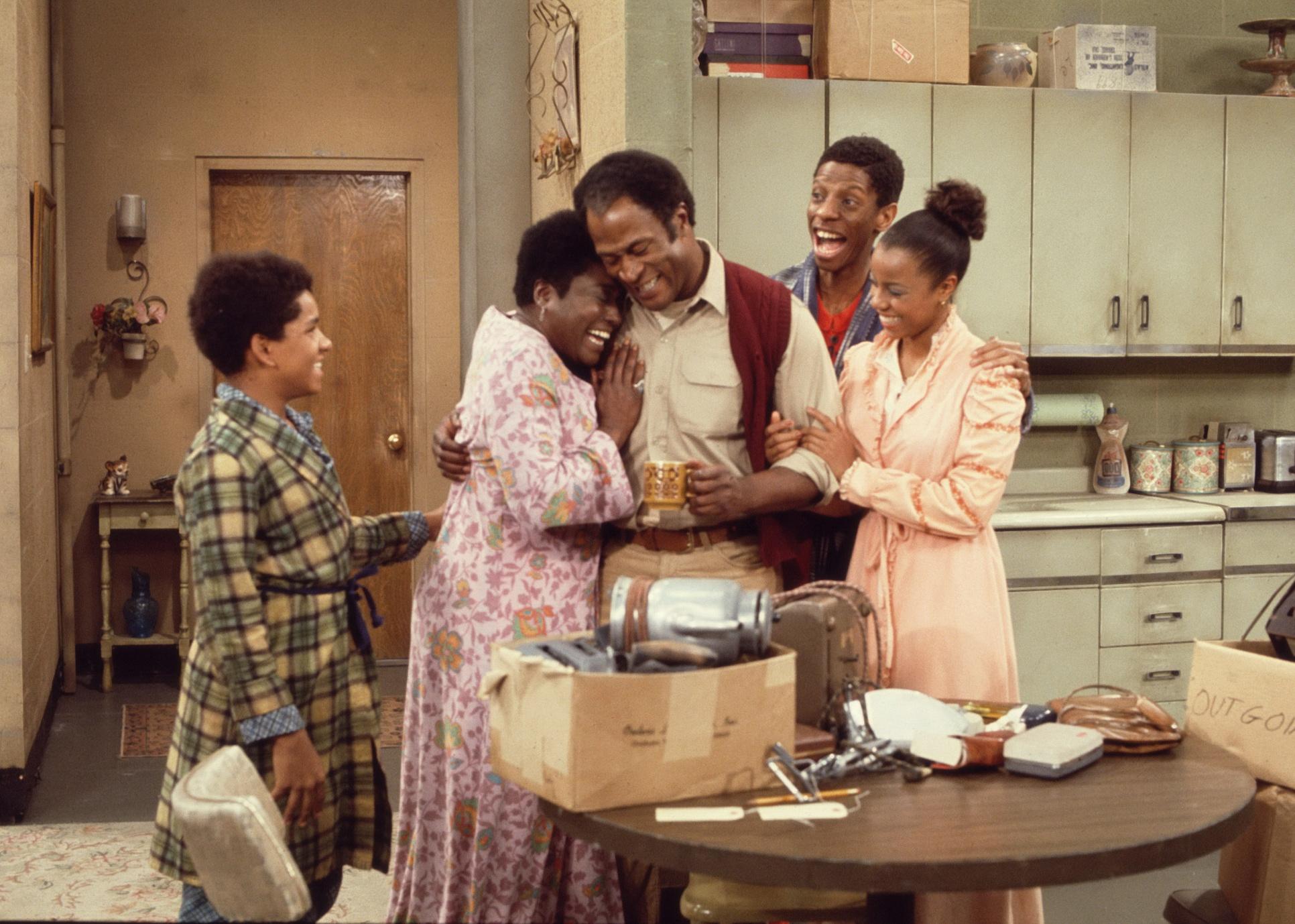 A family hugging and smiling in a kitchen.