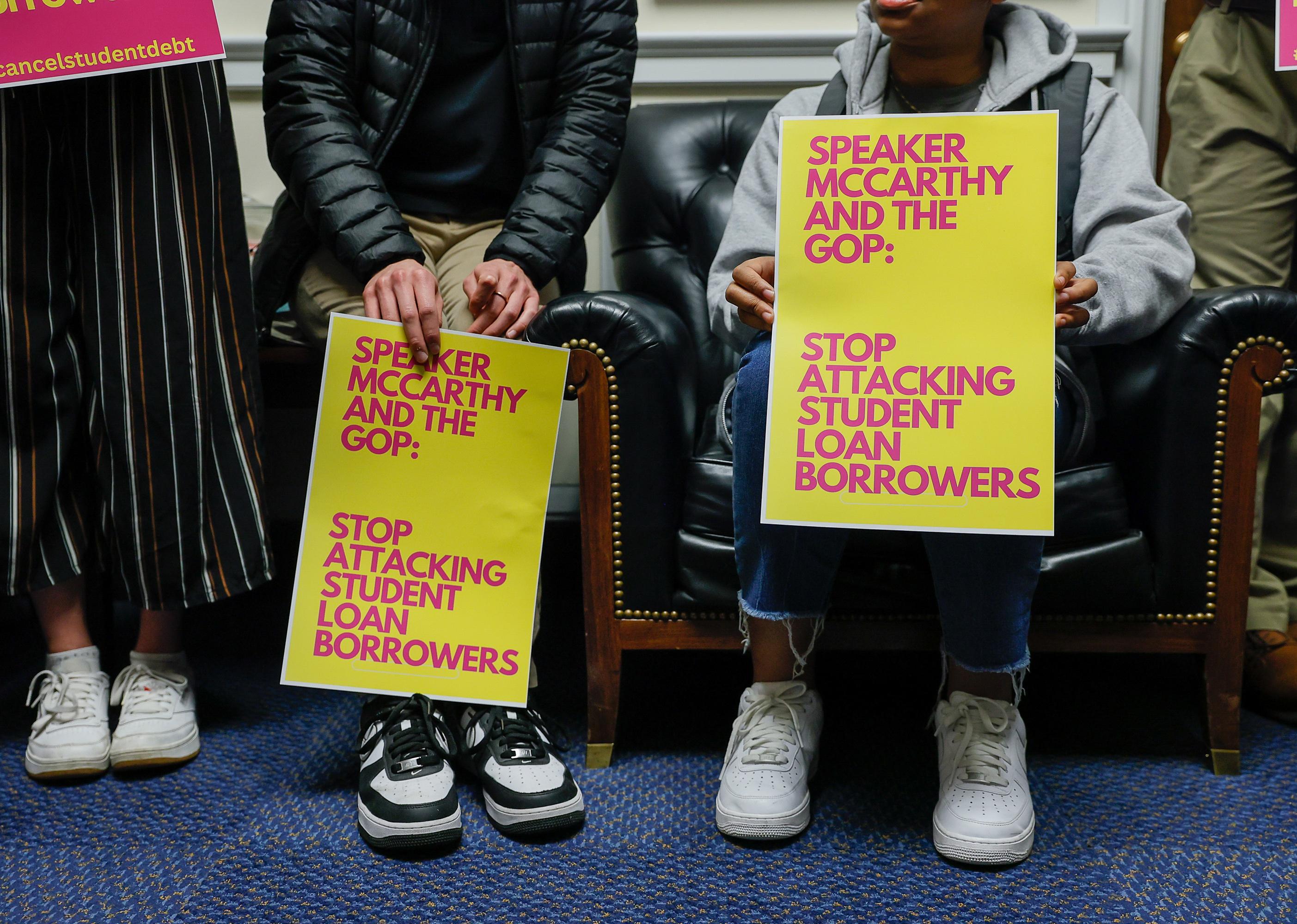Students holding signs for student loan forgiveness.