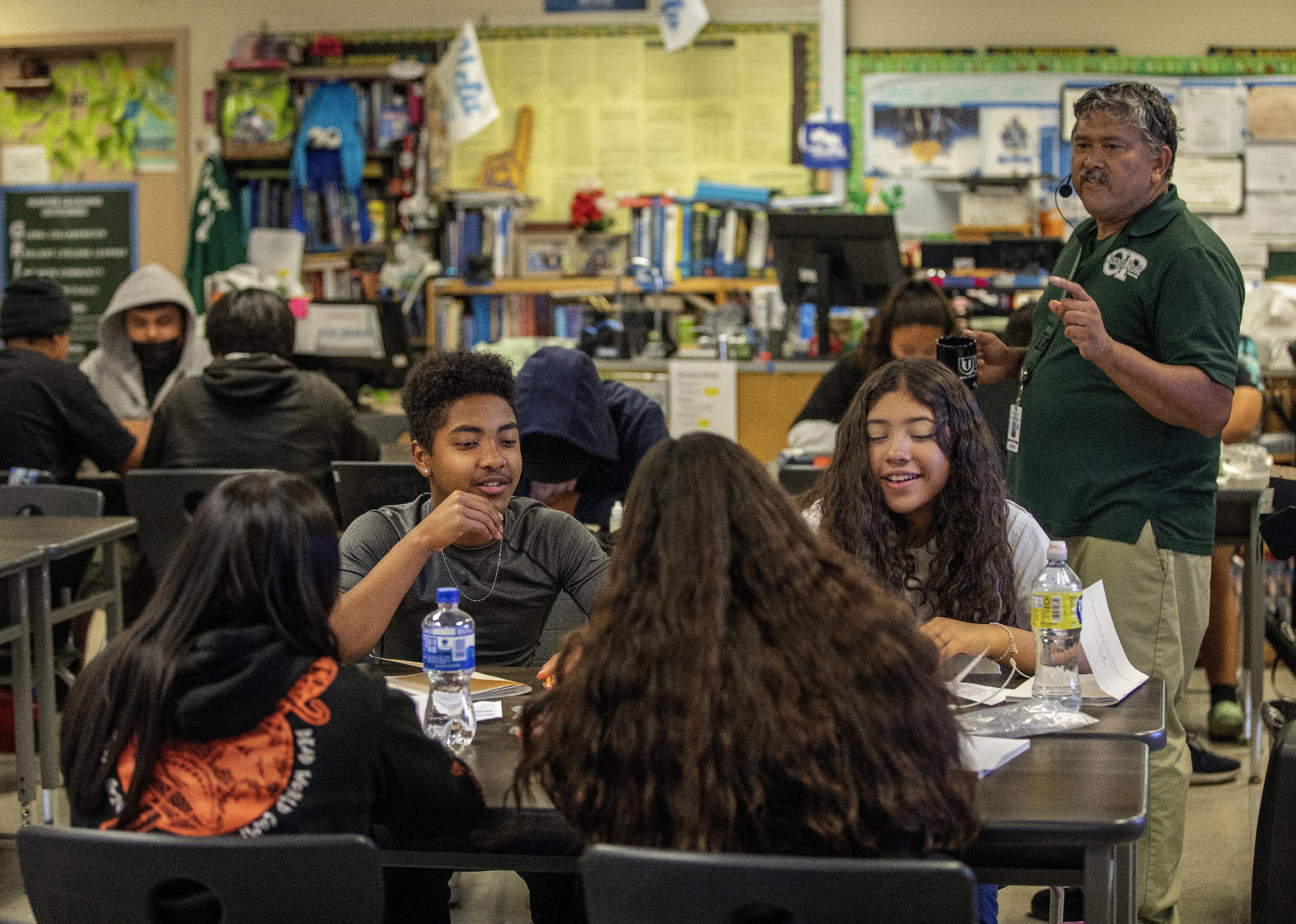 Students gathered at group tables in a classroom.