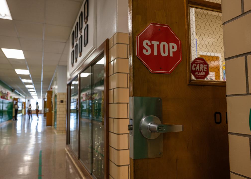 Almost empty hallway of a school with a stop sign on a door.