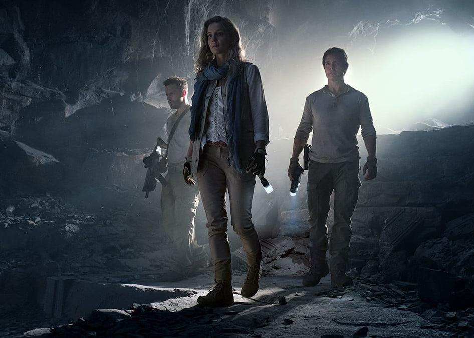 Three people in a dark cave with flashlights.