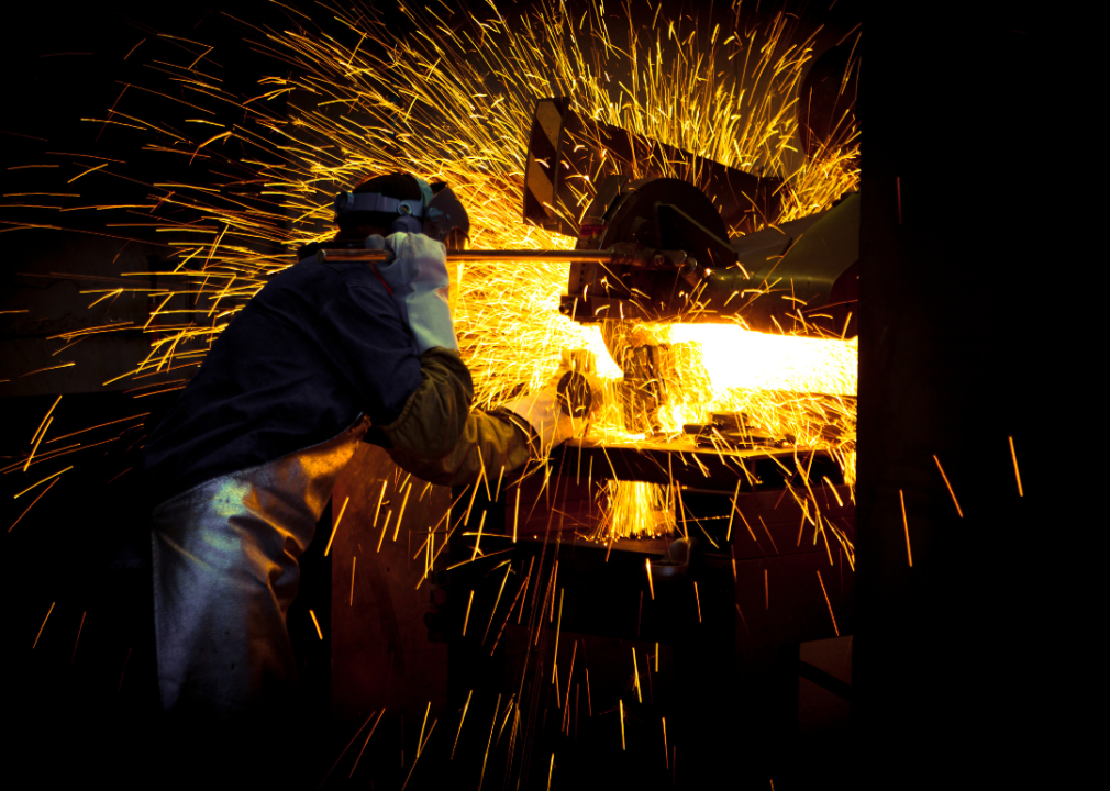 A worker grinding steel surrounded by flying sparks.
