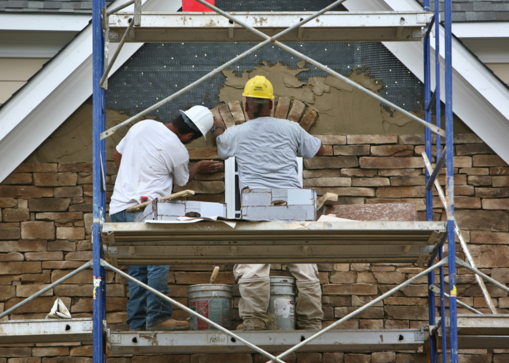 Two brickmasons laying stones.