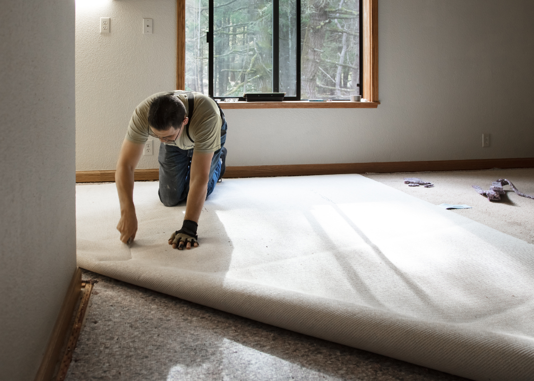 Person installing carpet in home. 
