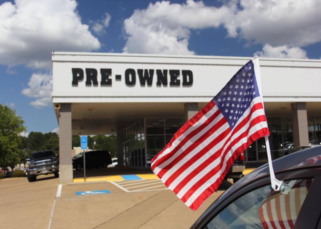 A used car lot with an American flag.