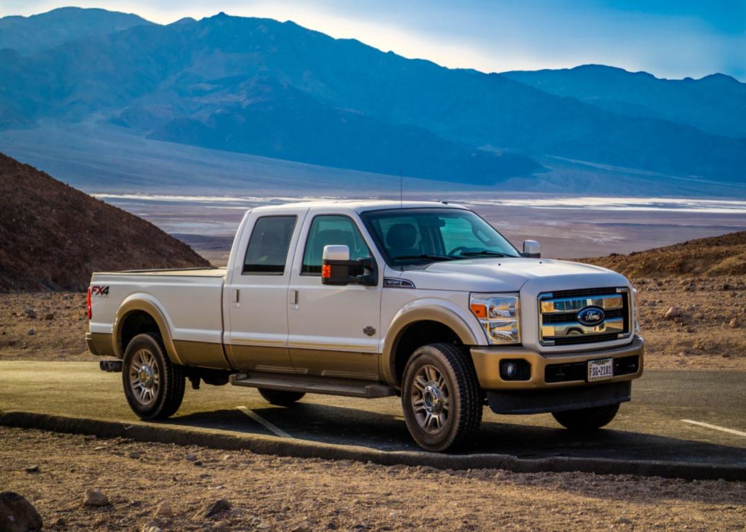 A white extended cab Ford truck with mountains in the background.