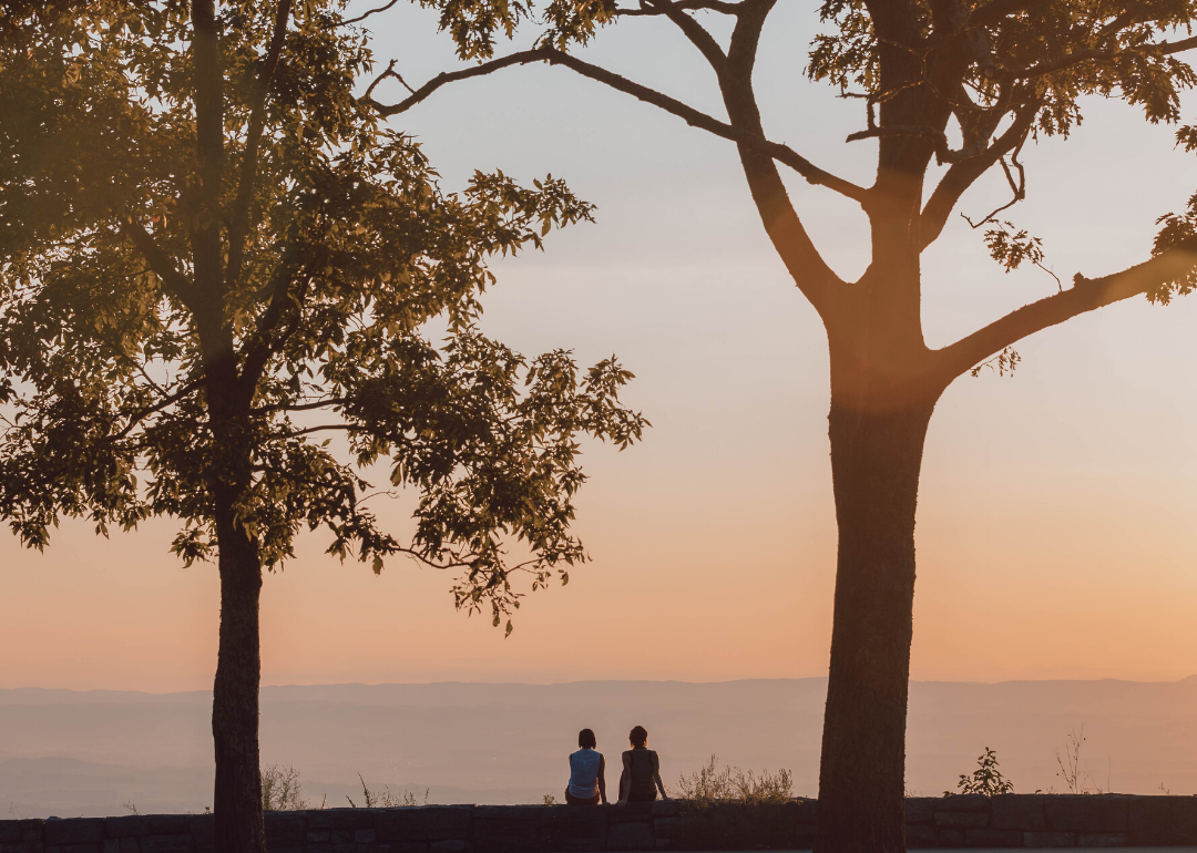 Two women watch the fading light from a high point.