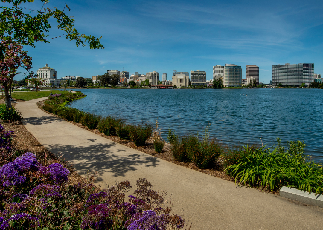 A walking trail by a lake with Oakland in the background.