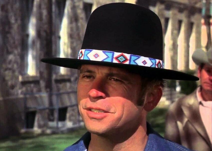 A man in a tall black hat with a turquoise beaded band around the brim.