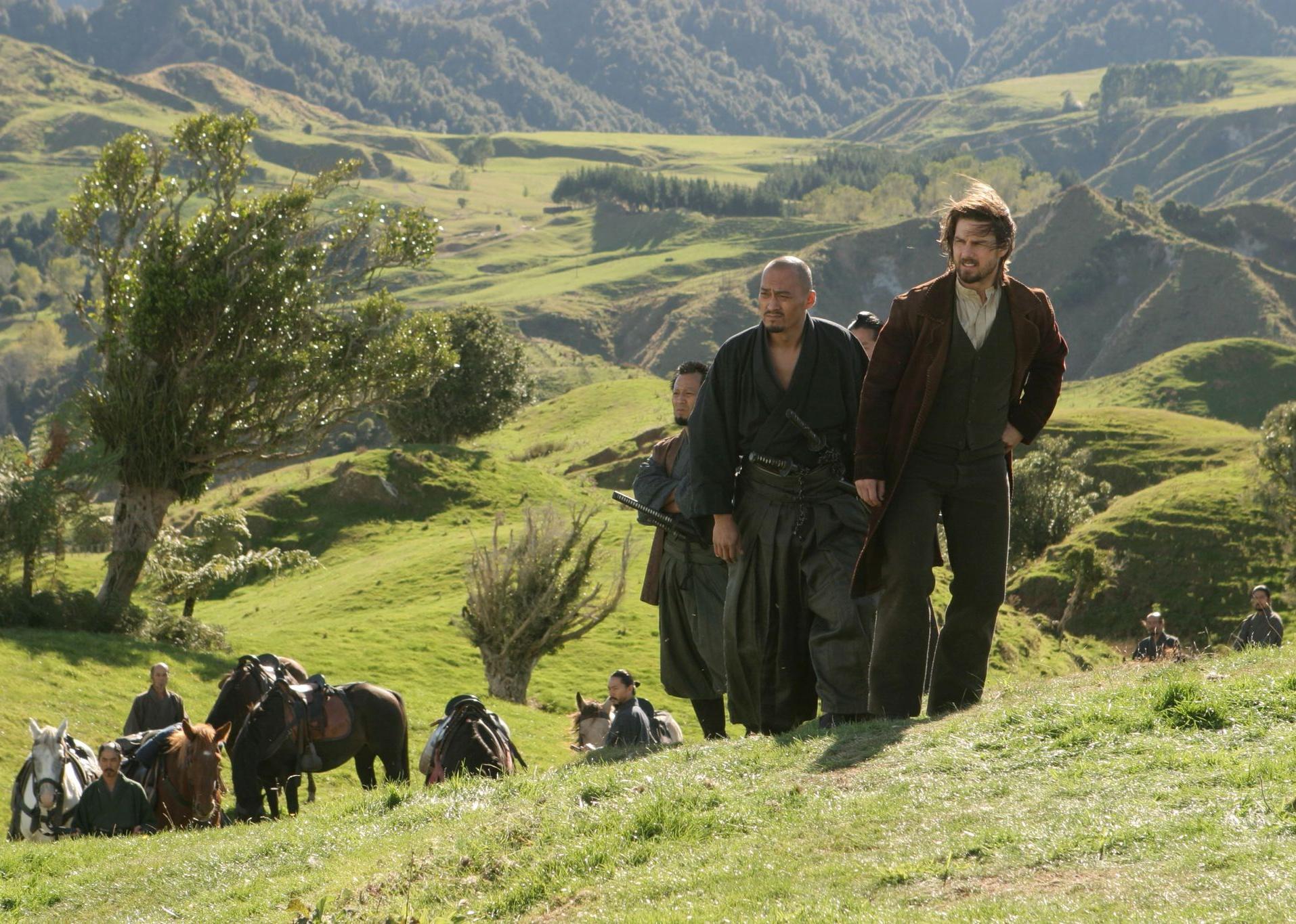 Tom Cruise, Shun Sugata, and Ken Watanabe walking up a hill with horses in the background.