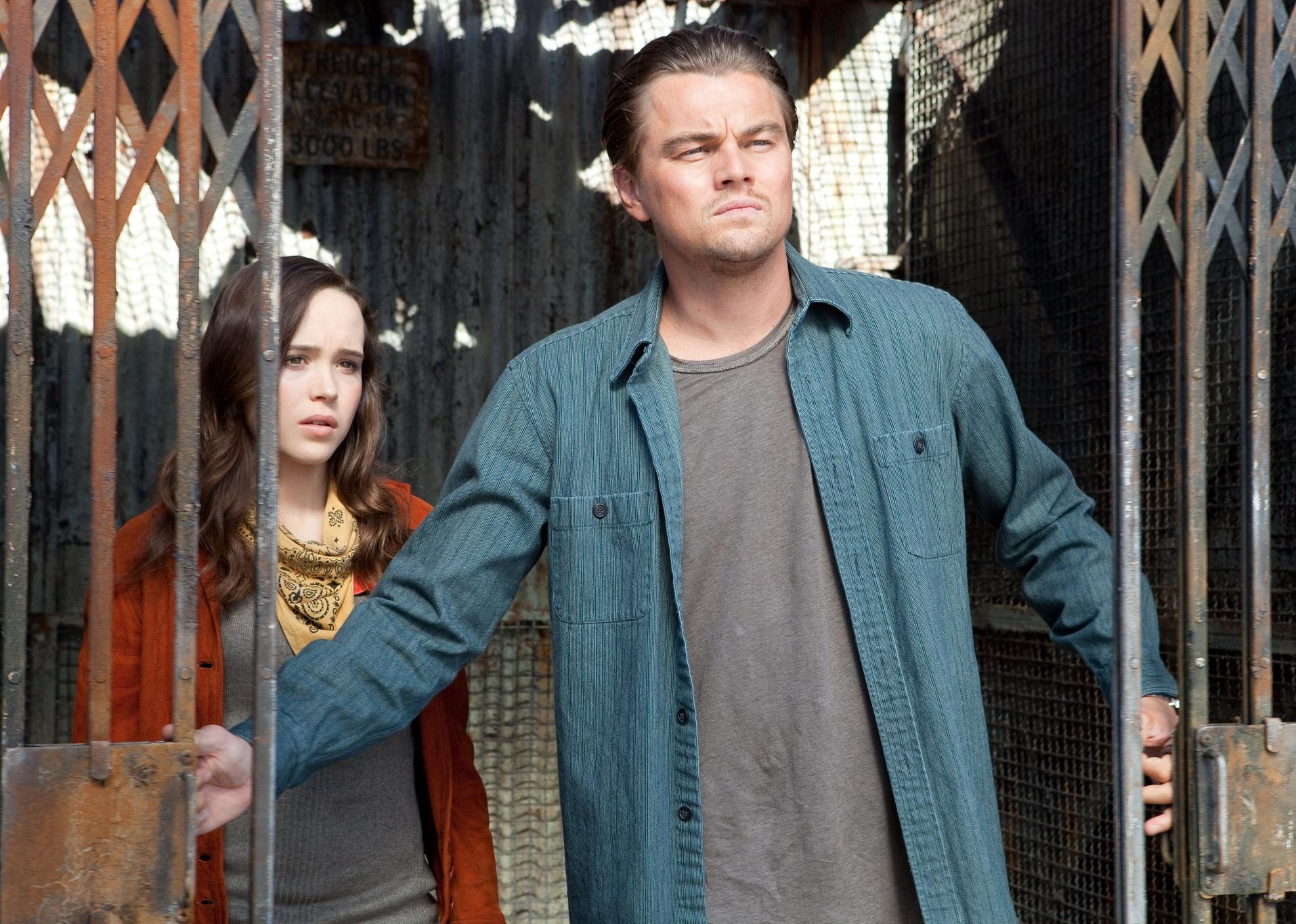 Leonardo DiCaprio and Elliot Page standing in the doorway of an old gate.
