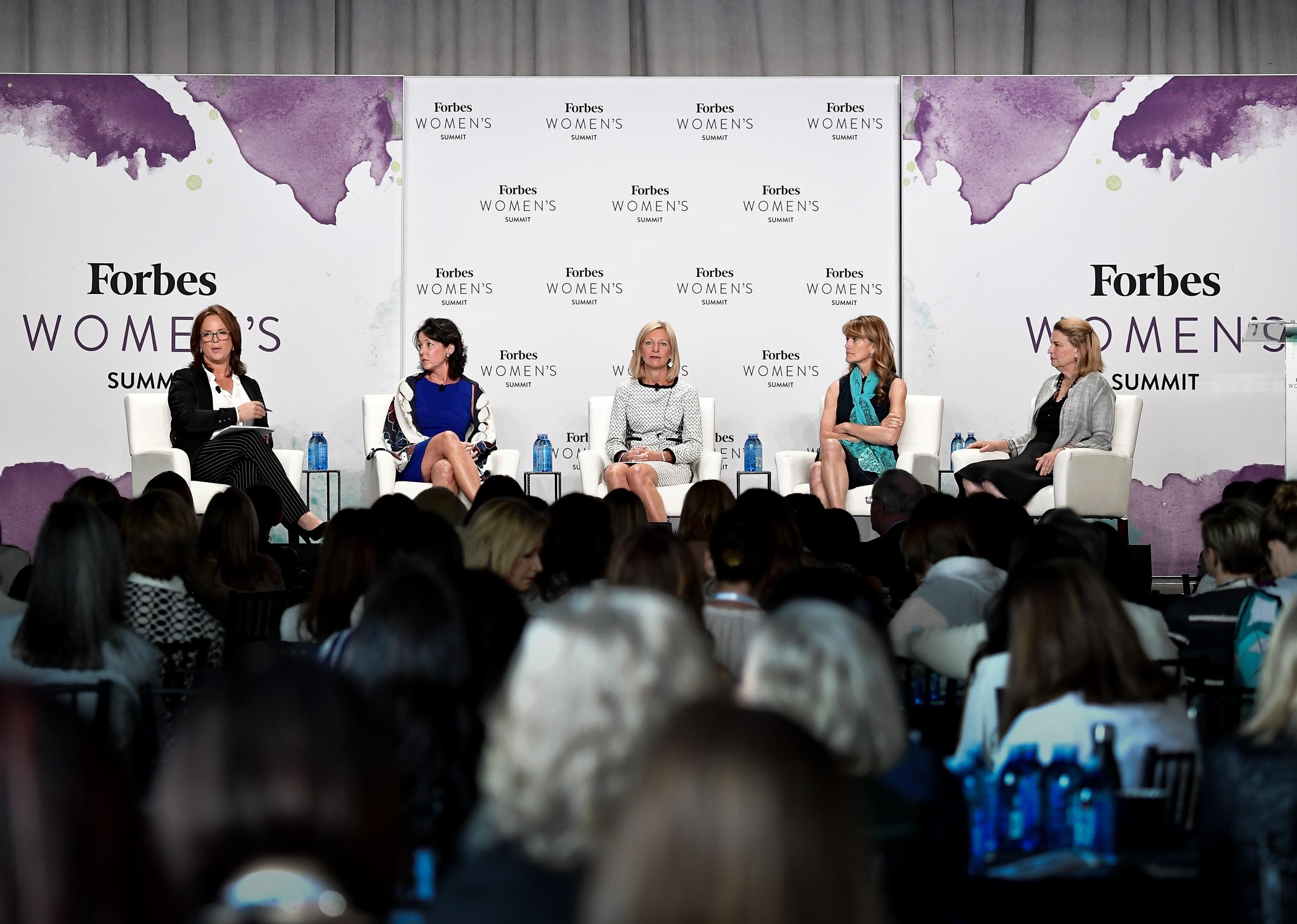 A panel of women onstage at the Forbes Womens Summit, with Karen Lynch in the center facing the crowd.