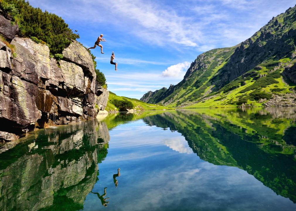 2 people jumping into water from a cliff.