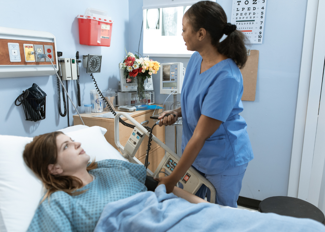 A nurse taking a patient's blood pressure in a hospital bed.