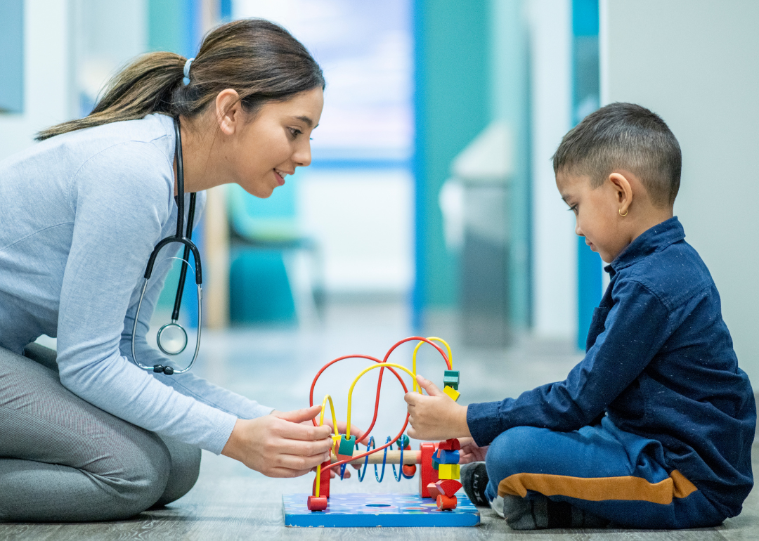 An occupational therapist working with a child while playing with a toy.