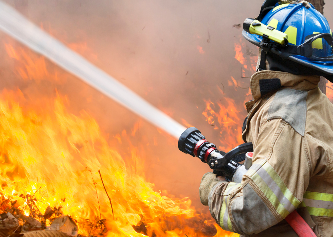 A firefighter hosing a wildfire.