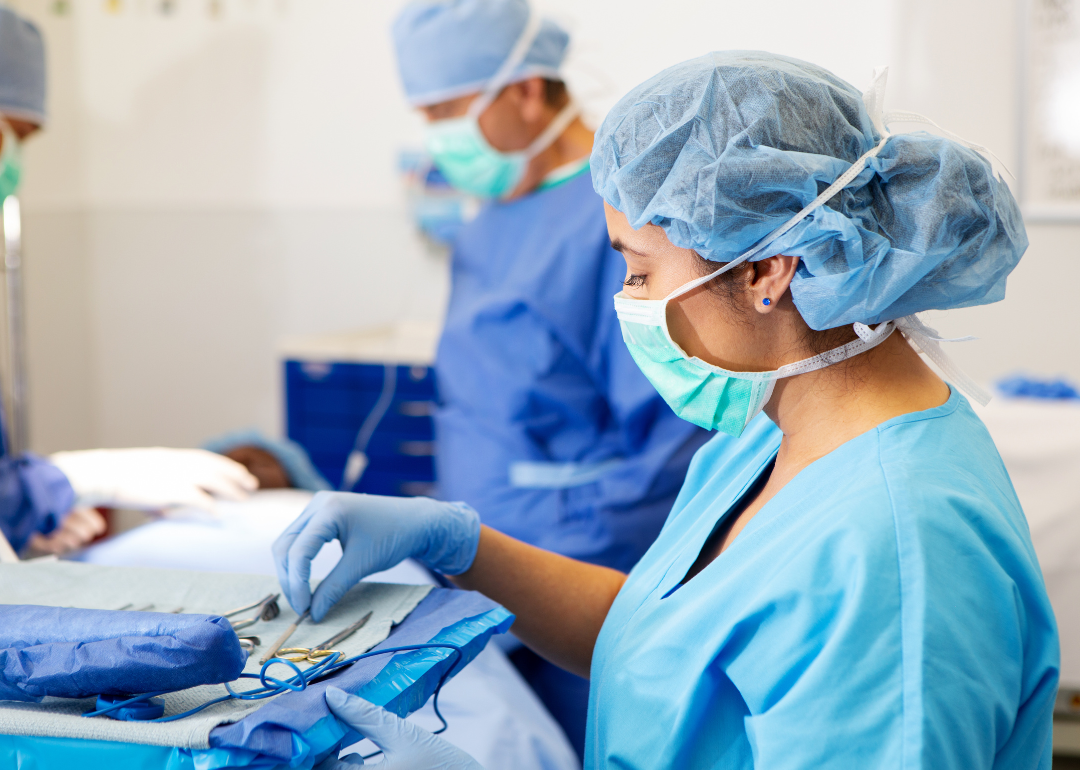 A surgical assistant holding a tray of tools during surgery.