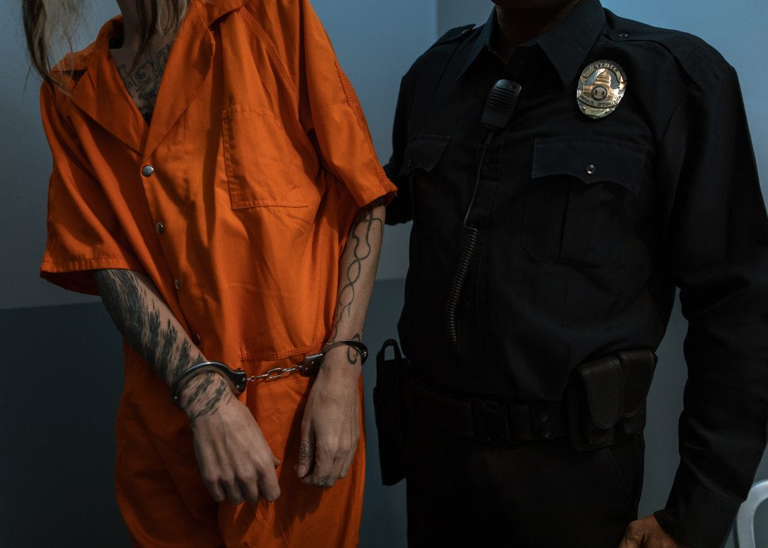 A correctional officer escorting a prisoner in an orange jumpsuit.