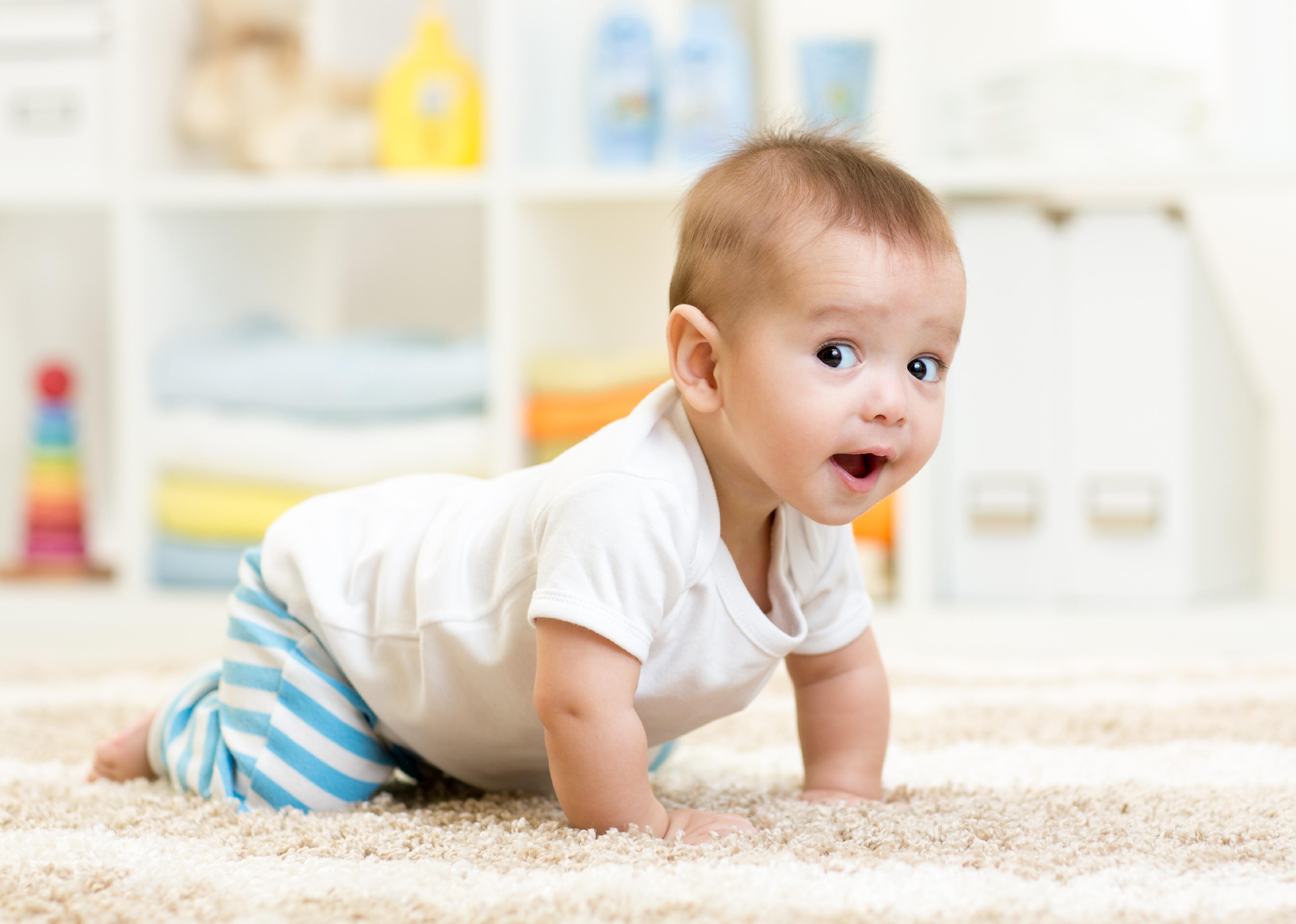 Baby crawling on white carpet.