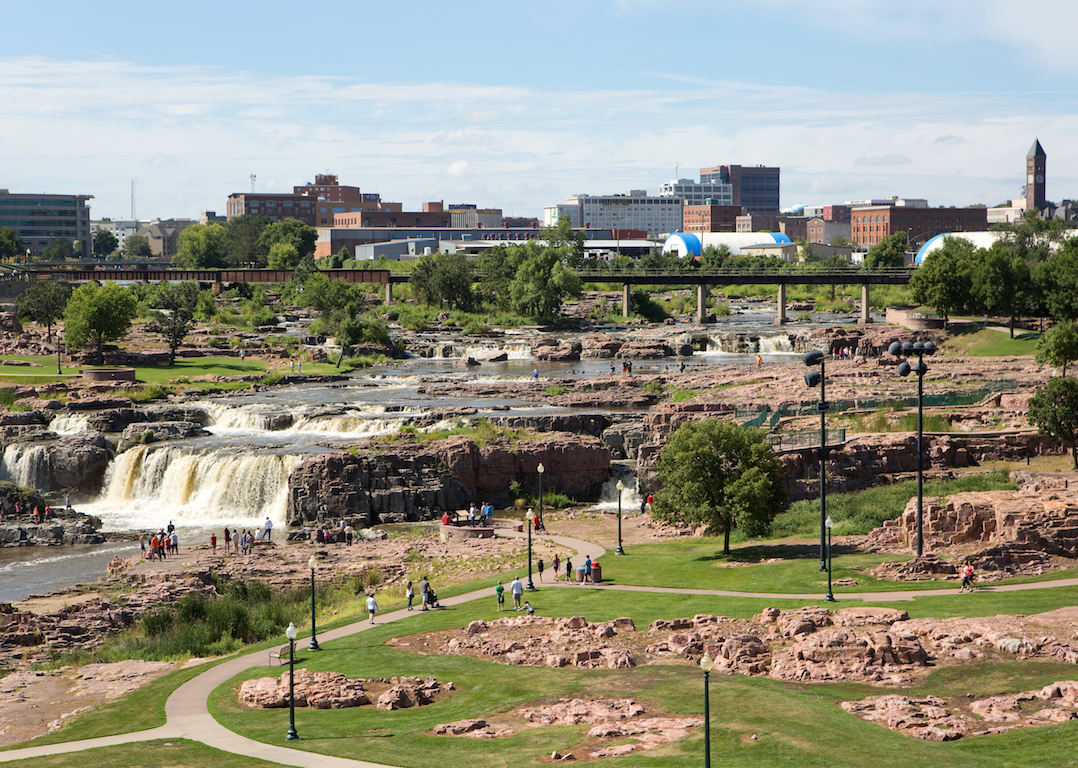 People walking around a park with waterfalls in the center.