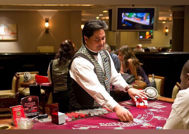 A Blackjack dealer deals cards at a table in a casino. 