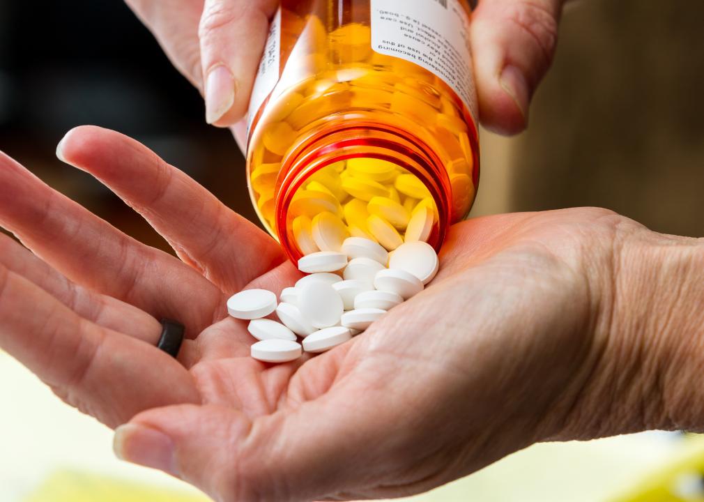 Close up someone pouring prescriptions pills into their hand.
