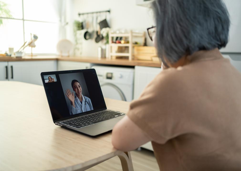 Asian senior woman video calls with doctor in living room at home