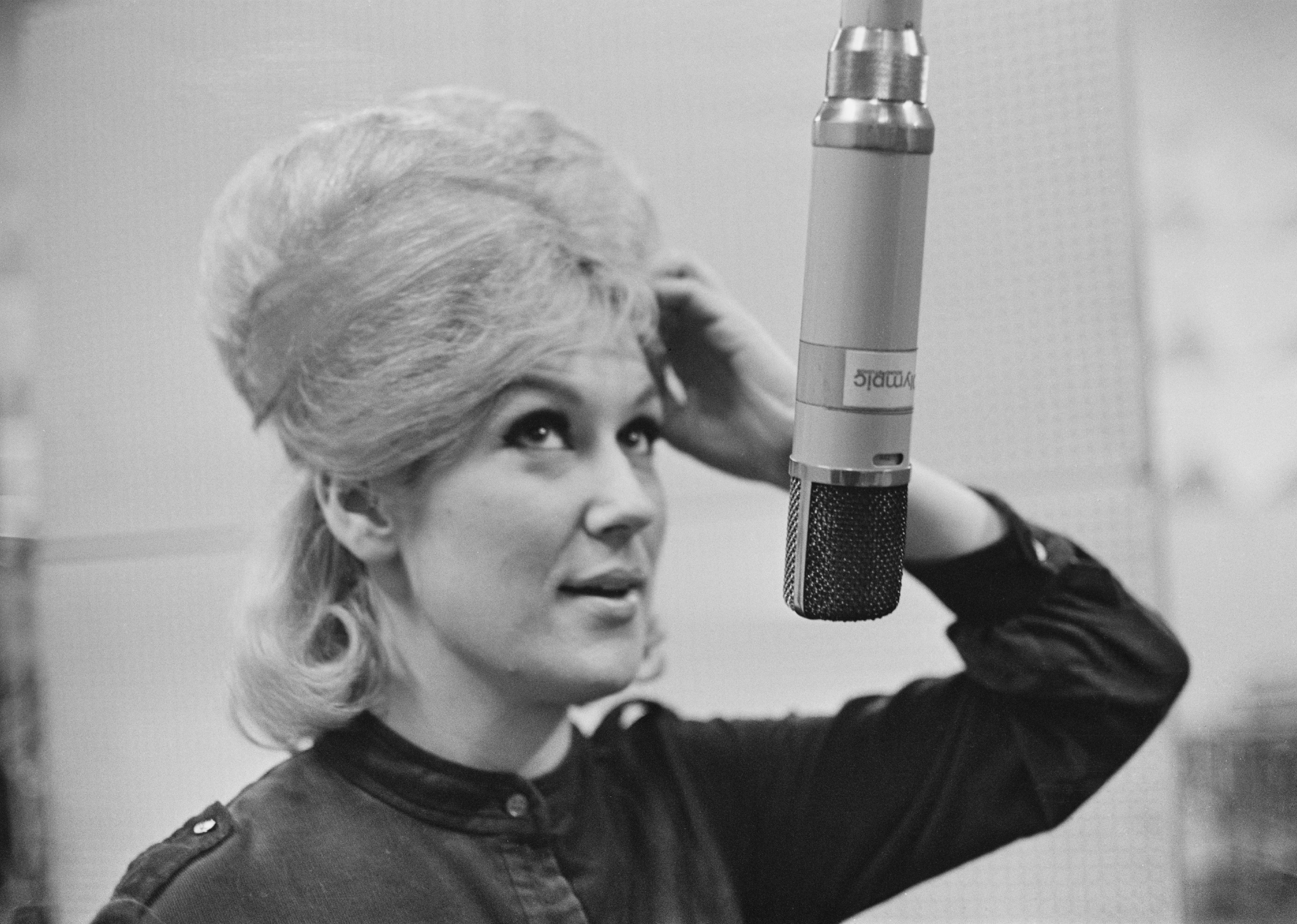 Dusty Springfield singing into a studio microphone.