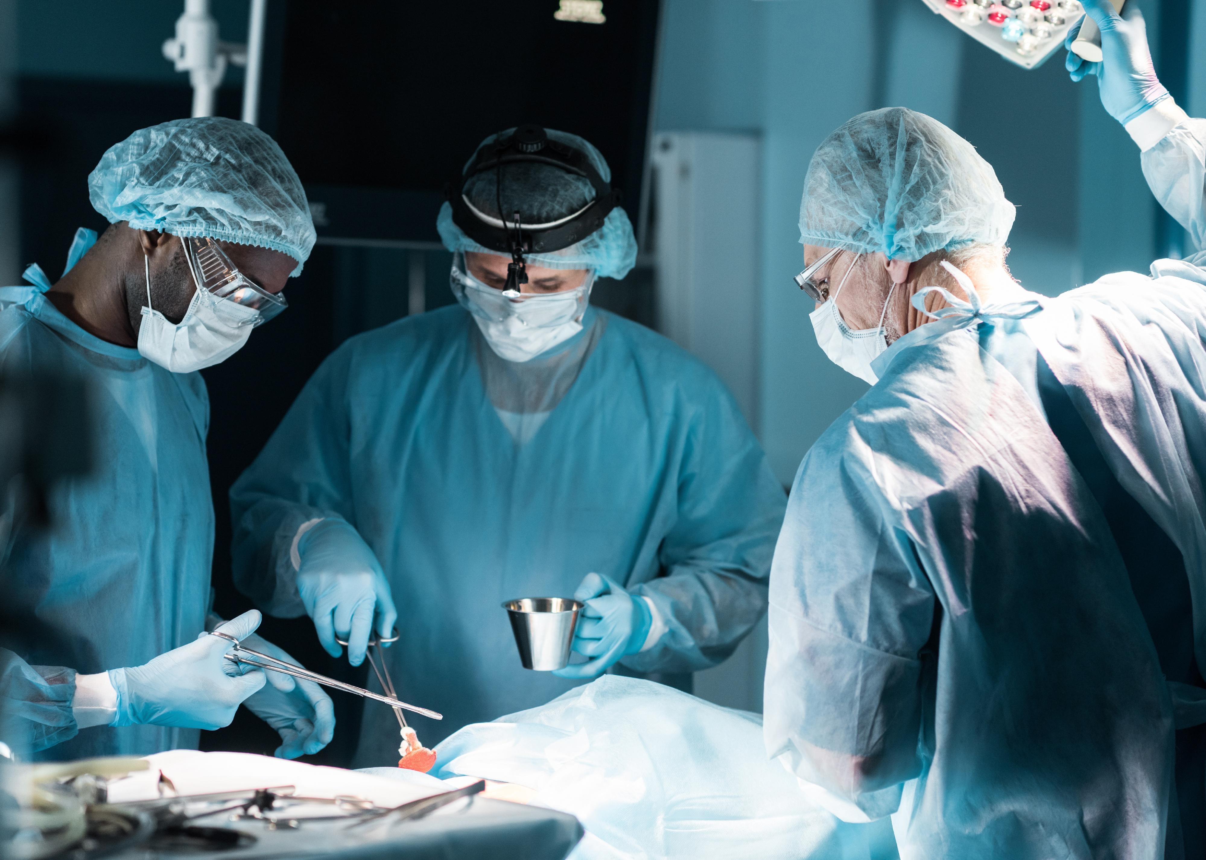 Surgeons in medical masks operating on a patient in operating room.
