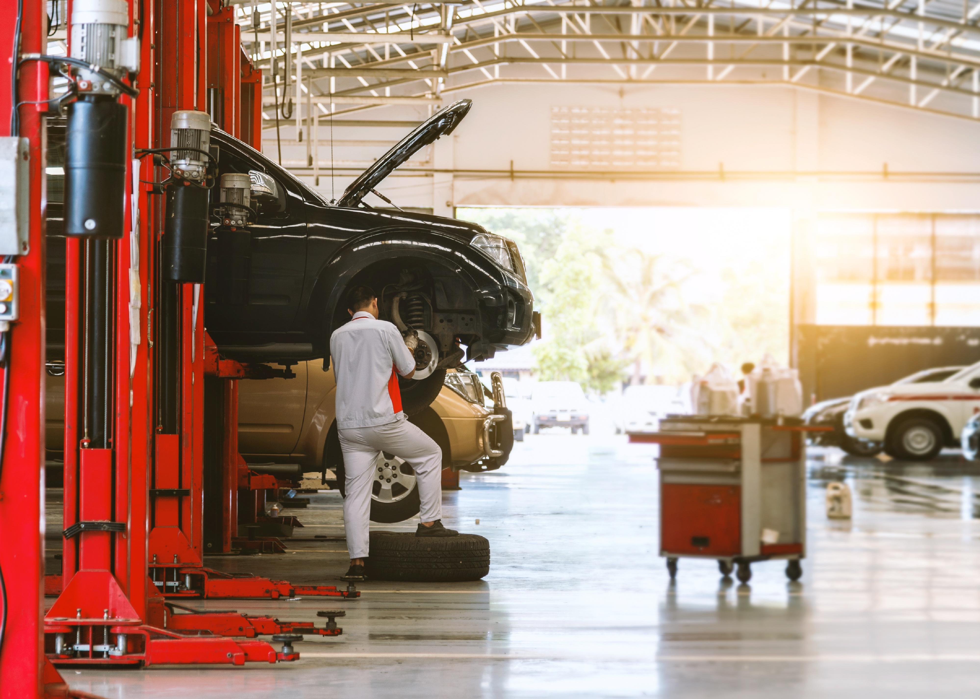 Car repair shop with man working on raised car