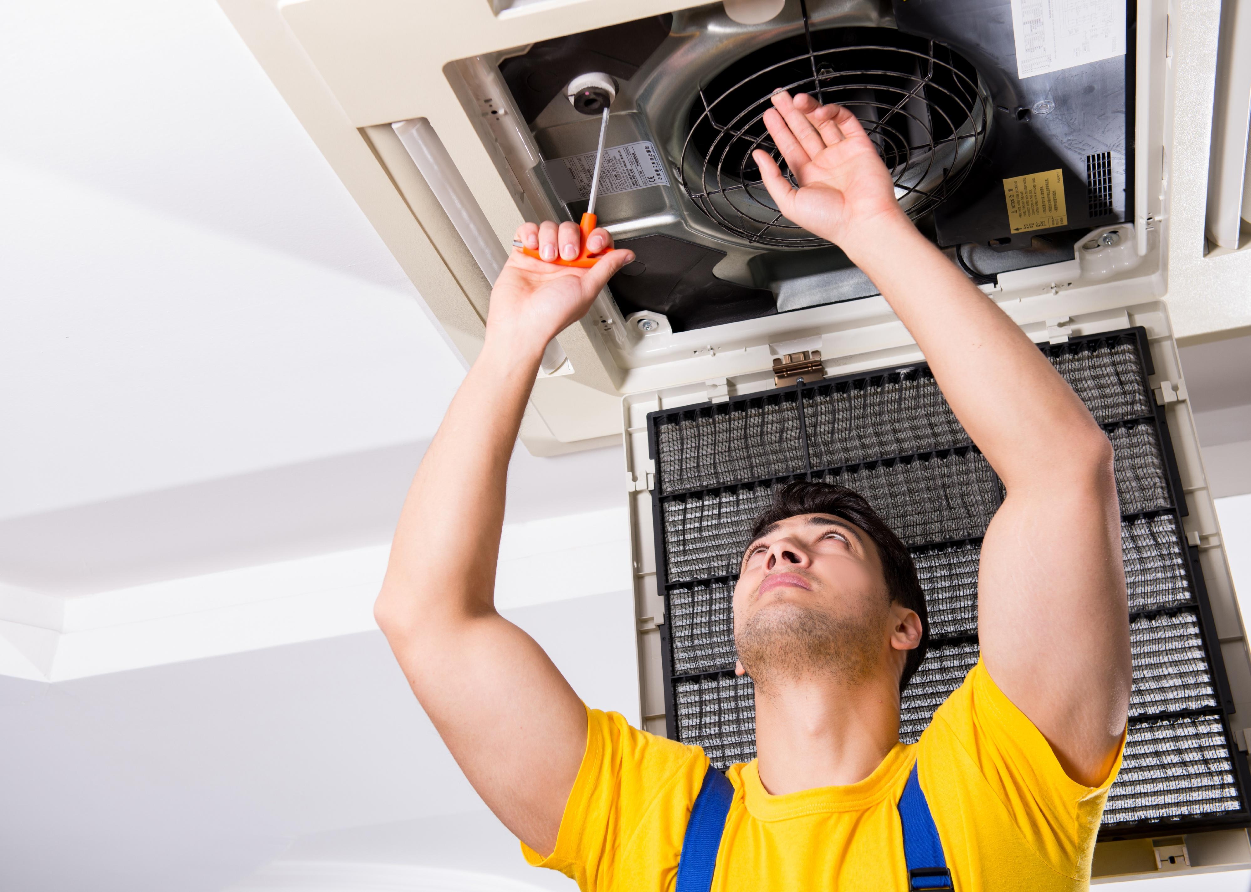 Person repairing ceiling air conditioning unit.