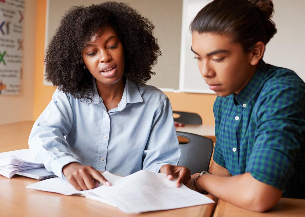 A tutor points to papers in front of her and a teen student she is working with.