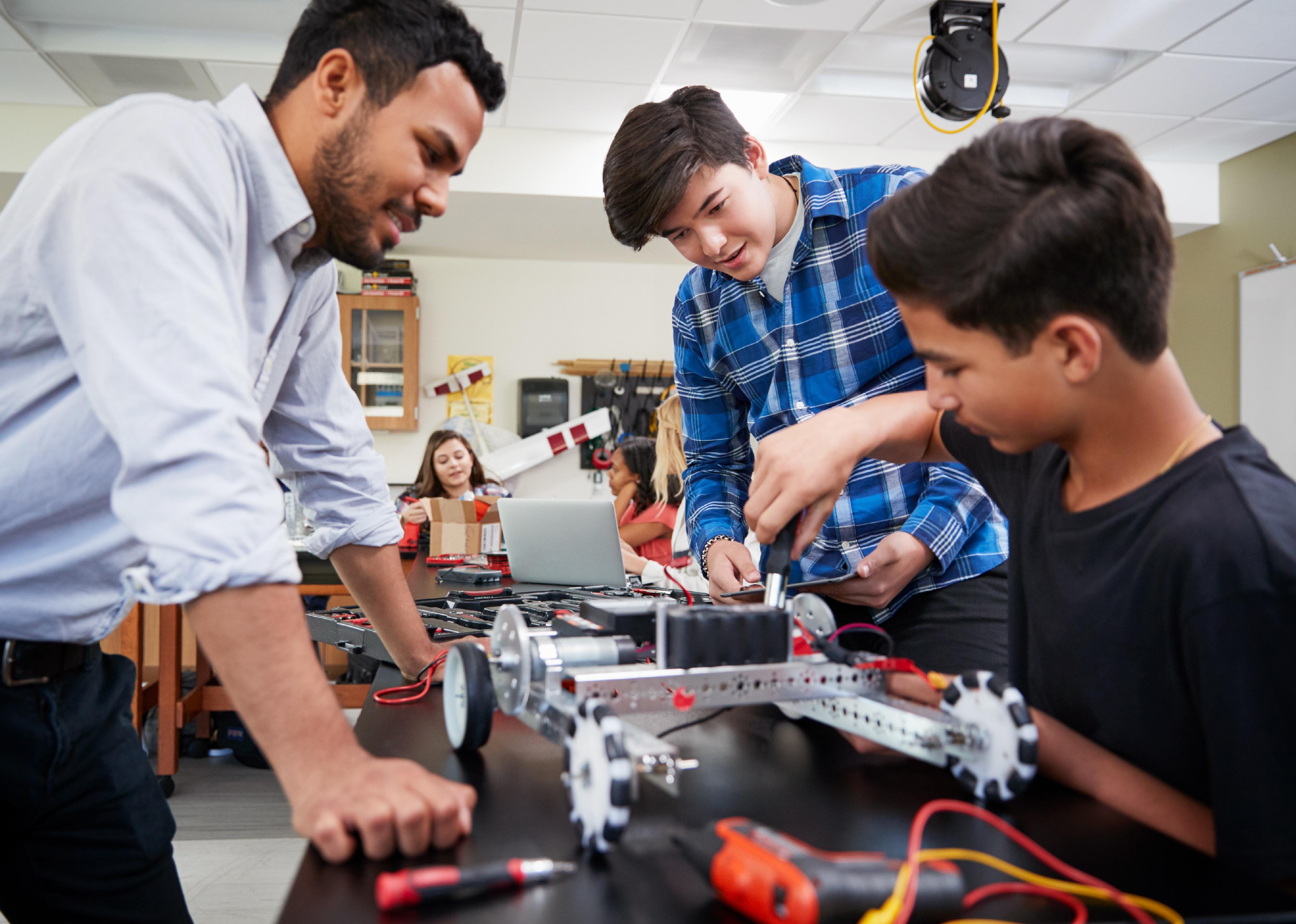 Teacher with students building robot 
