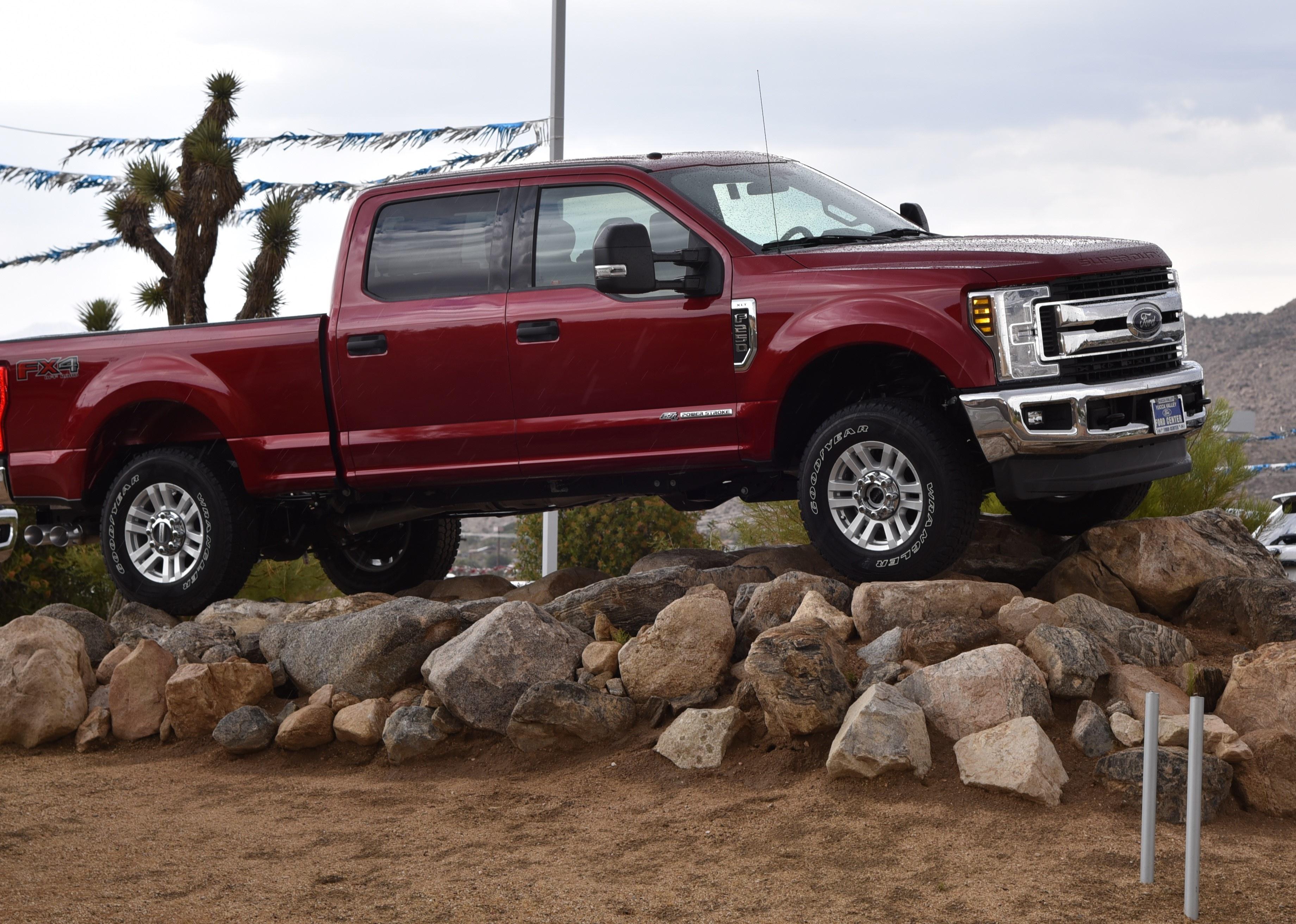 New red Ford F150 at a dealership on some rocks.