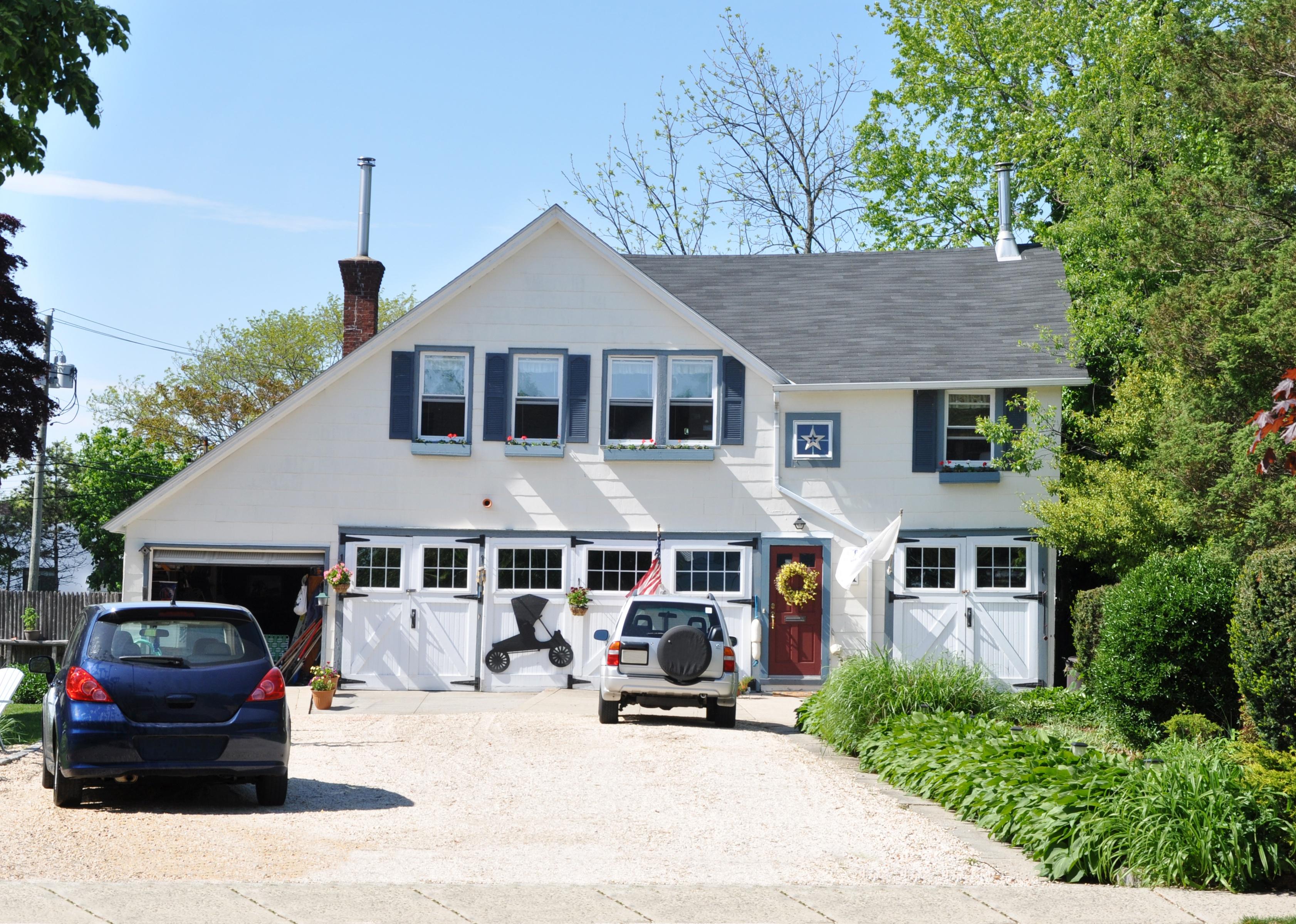 Country home with two cars in driveway on a sunny blue sky day.