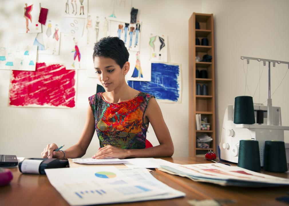 Young Hispanic woman checking bills and doing budget with calculator