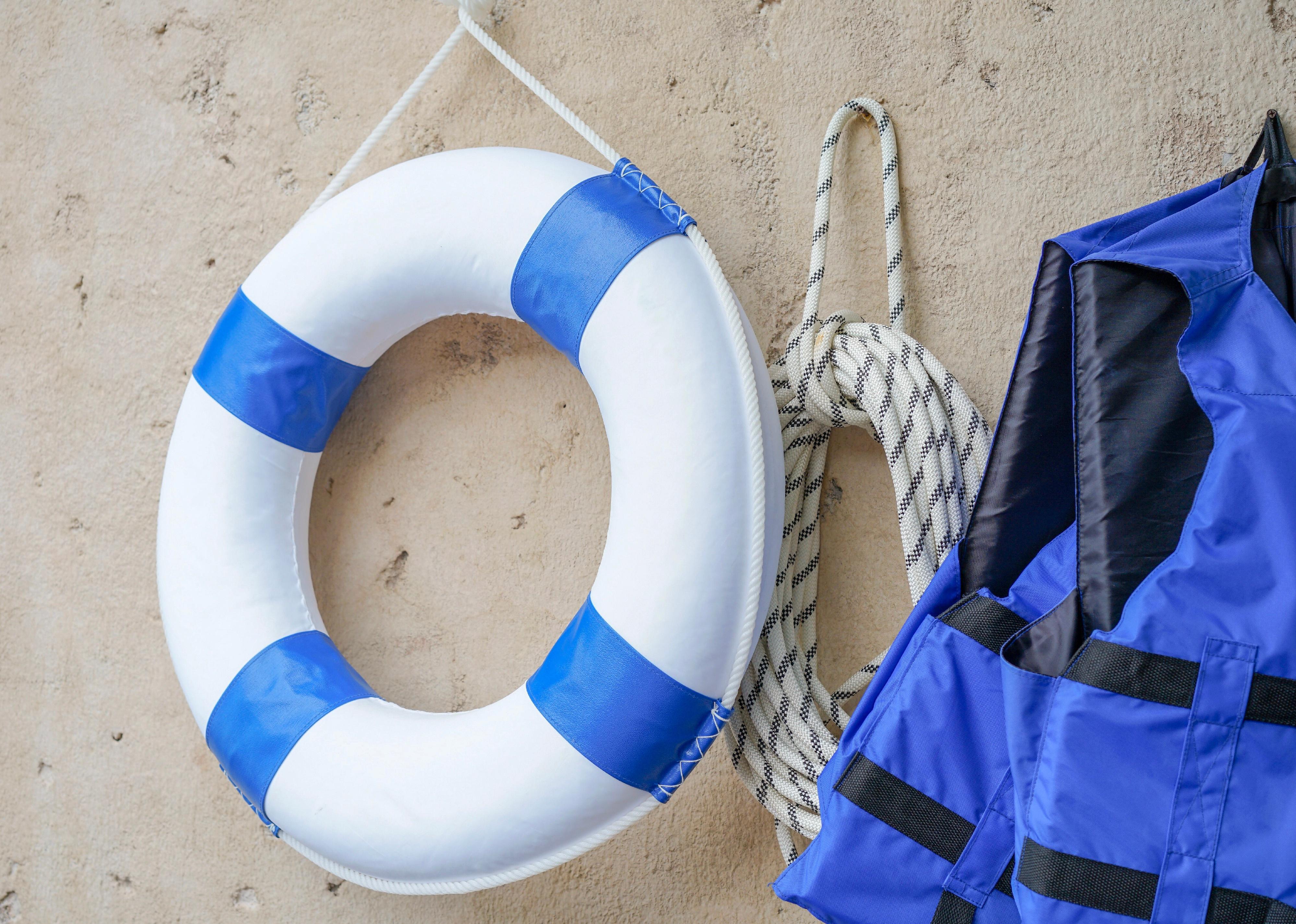 Roll of rope and life jacket on cement wall near the pool.