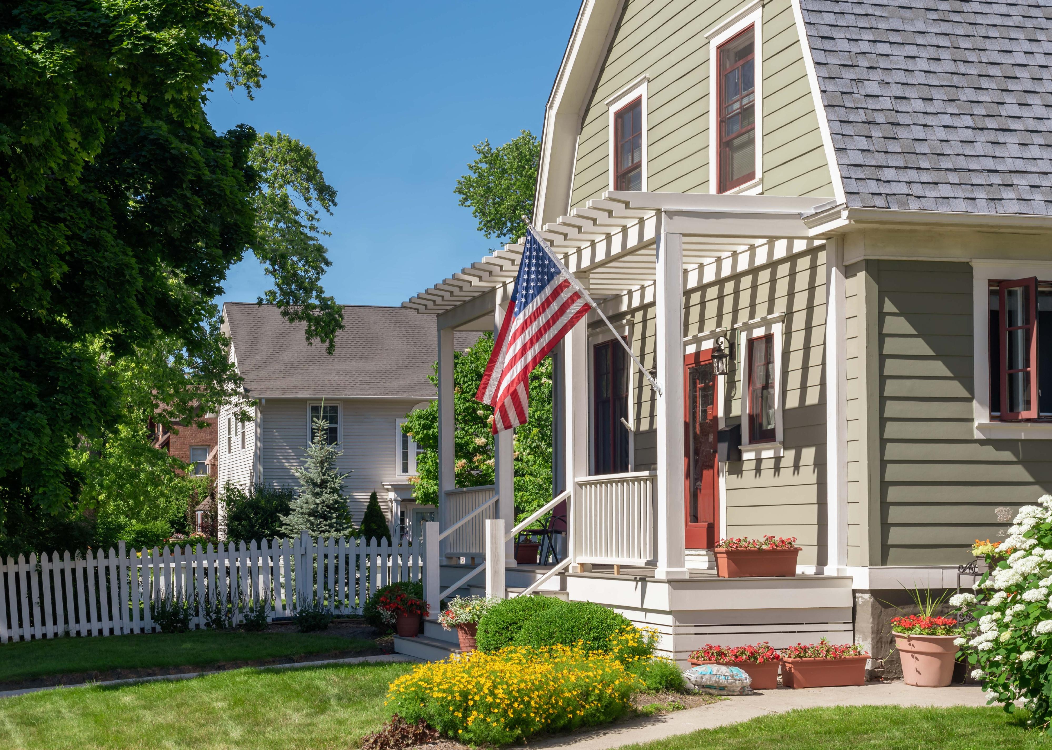 Home with U.S. flag and pergola front porch.
