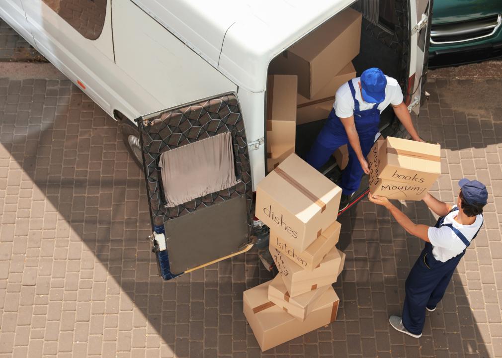 Male movers unloading boxes from van 