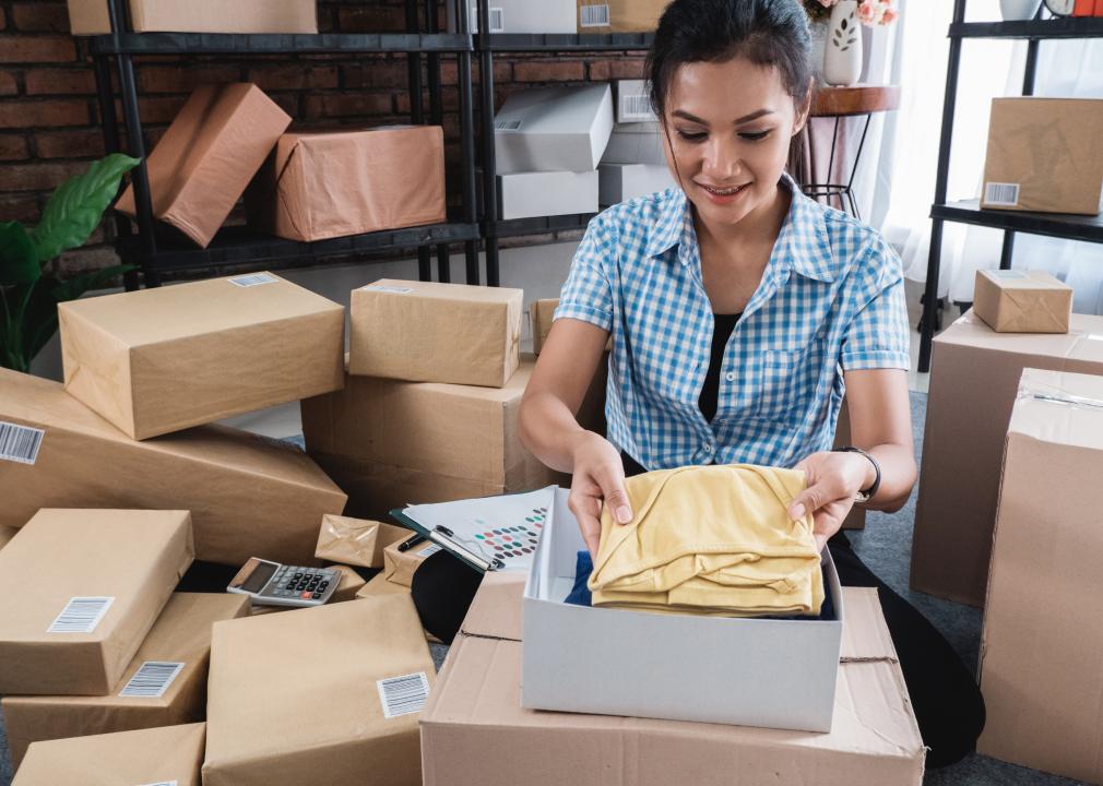 Young woman packing clothes in boxes to be shipped
