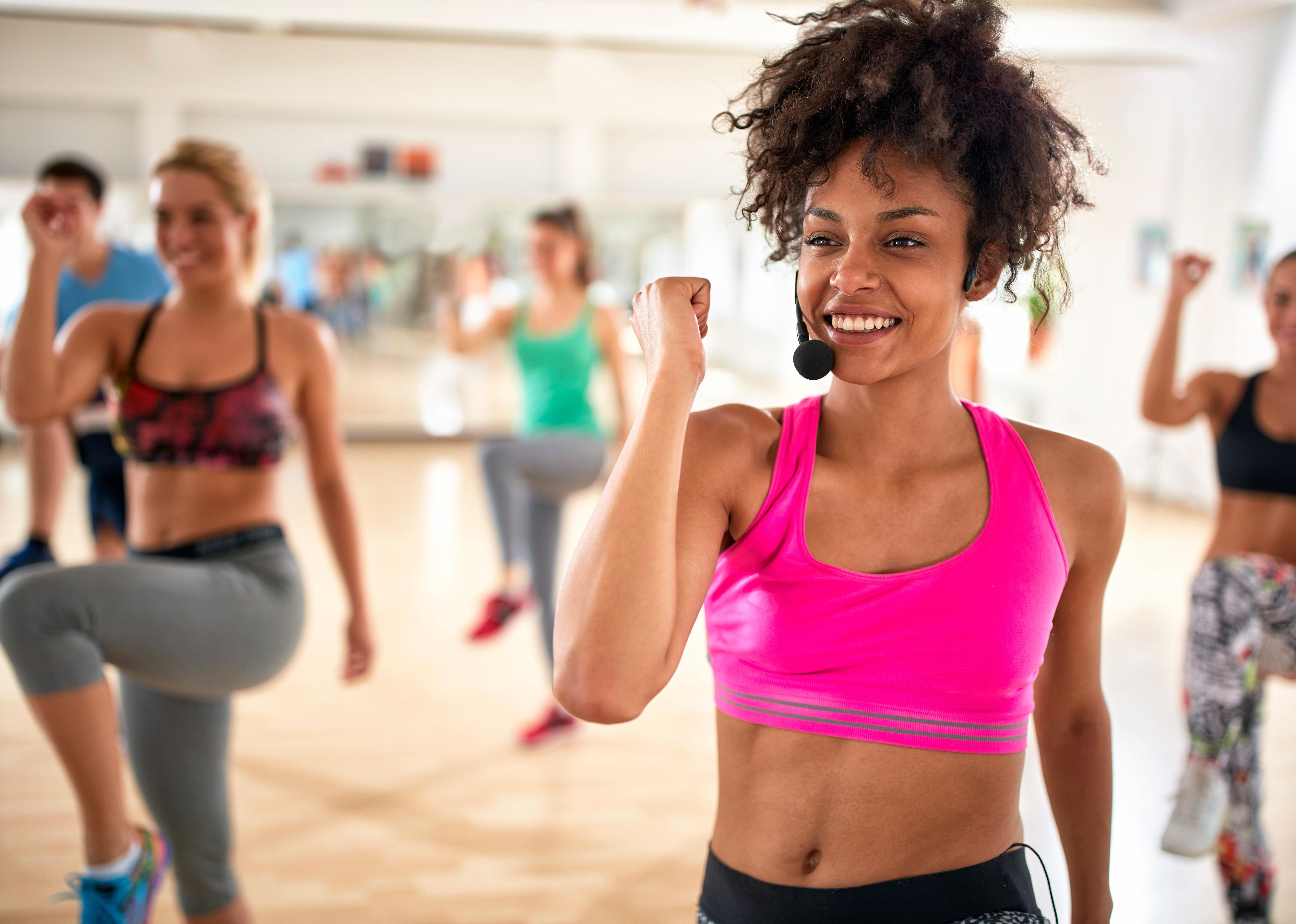 Woman instructor with headset in exercise class with group.