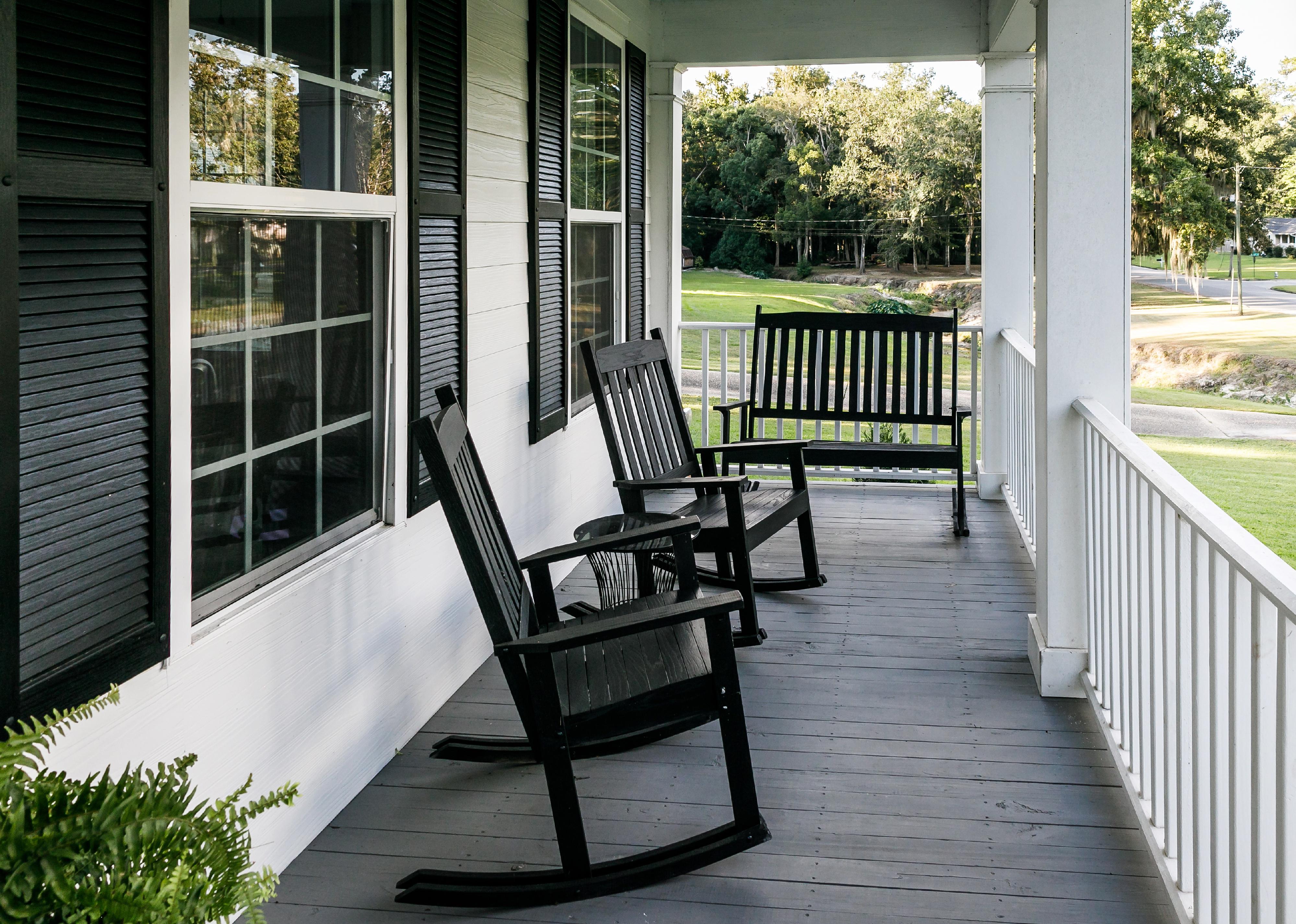 Front porch of Southern home with black rocking chairs.
