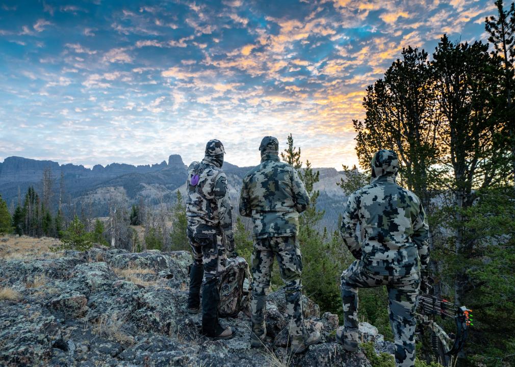 Three hunters on a mountain ridge looking for elk. 