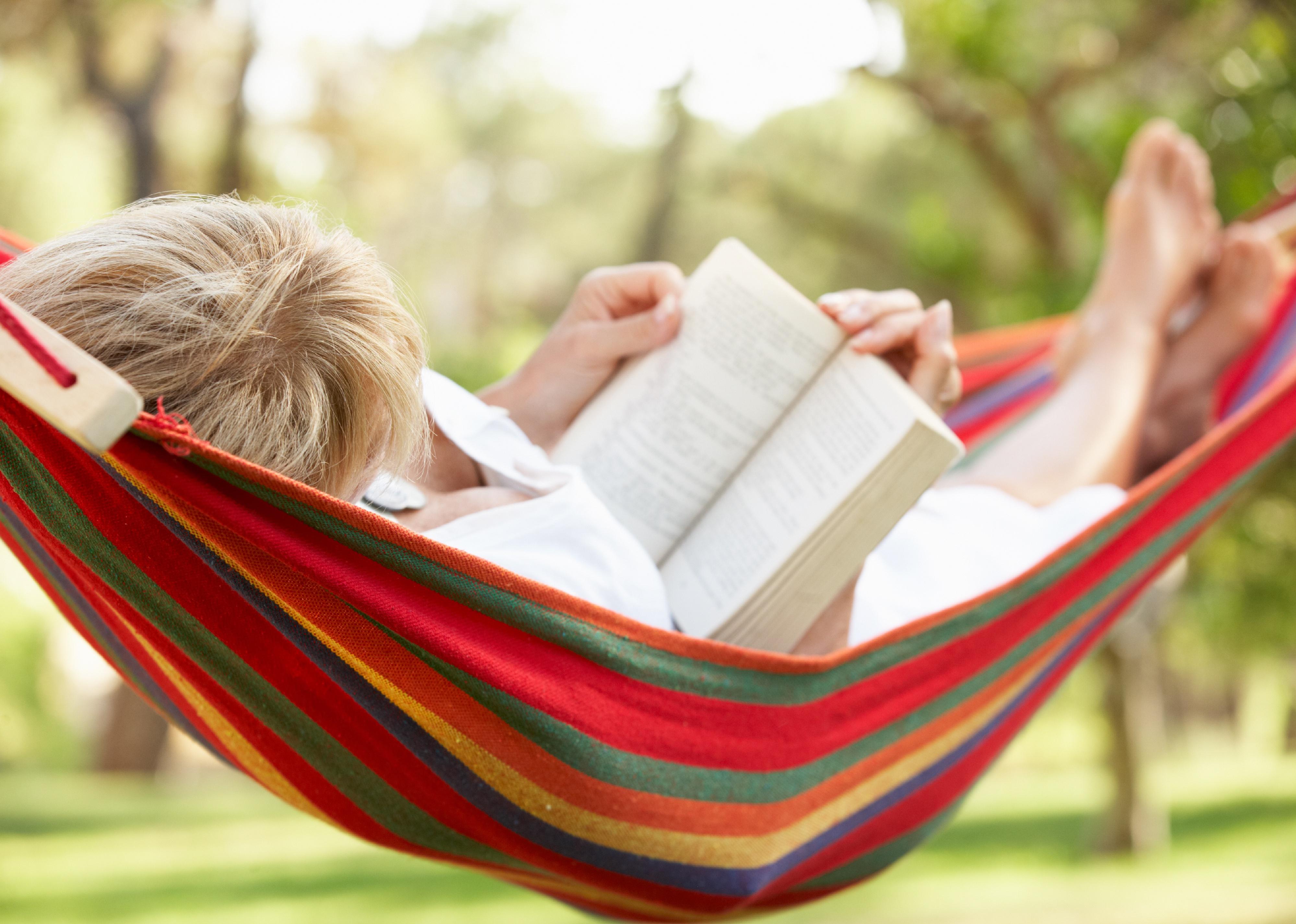 Senior woman relaxing in hammock with book.