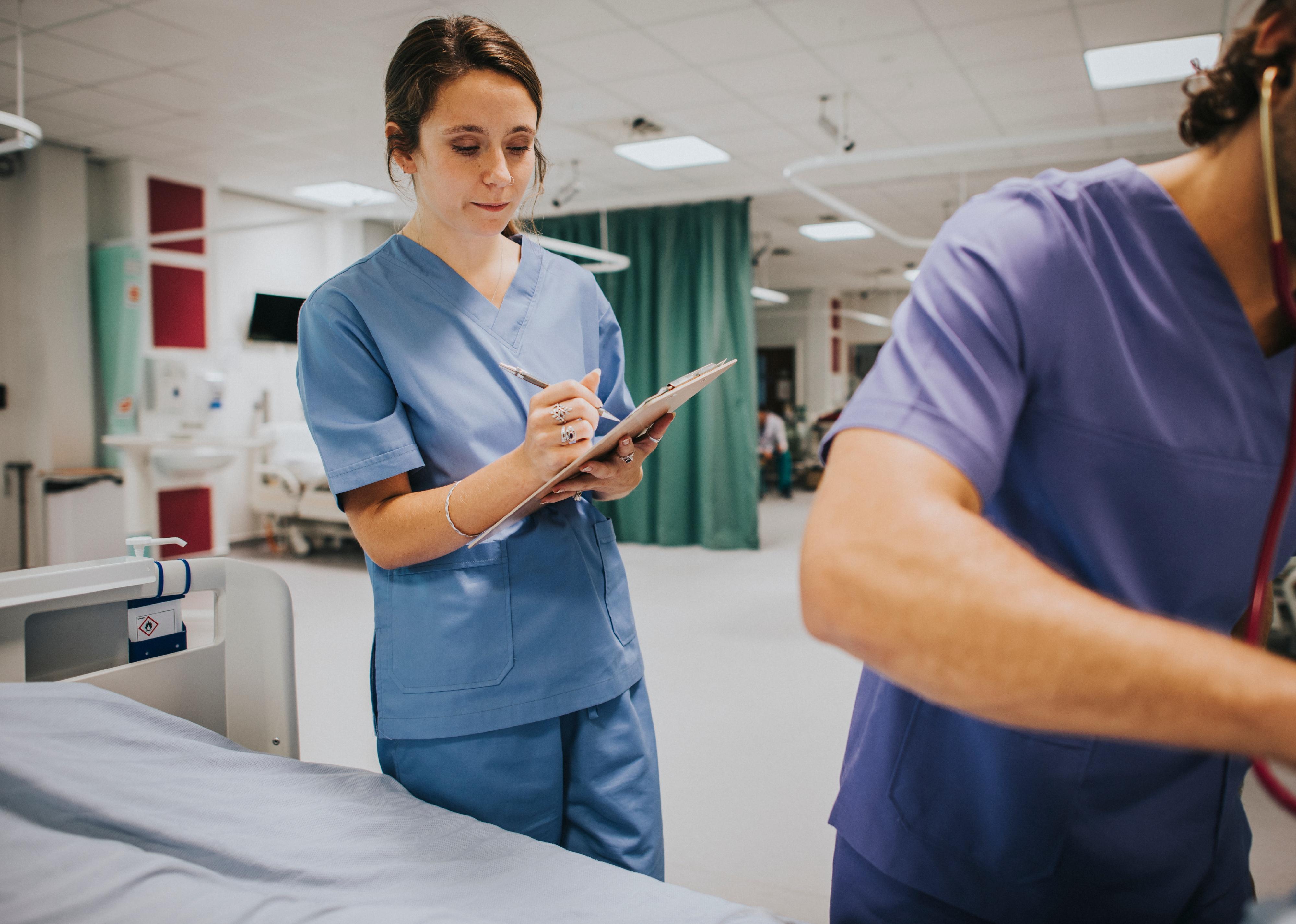 Health care worker writing on clipboard.