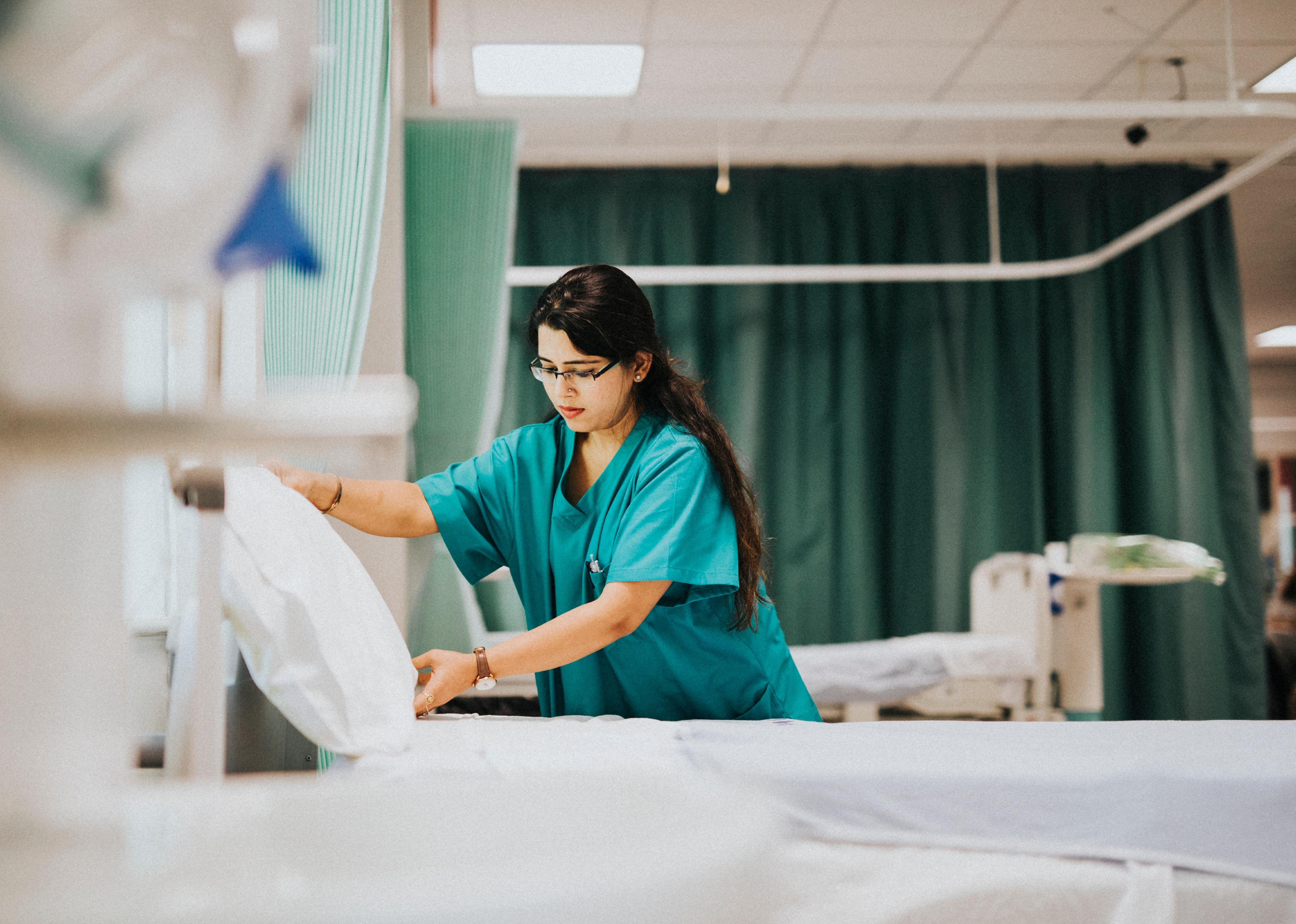 Nurse making the bed at a hospital.