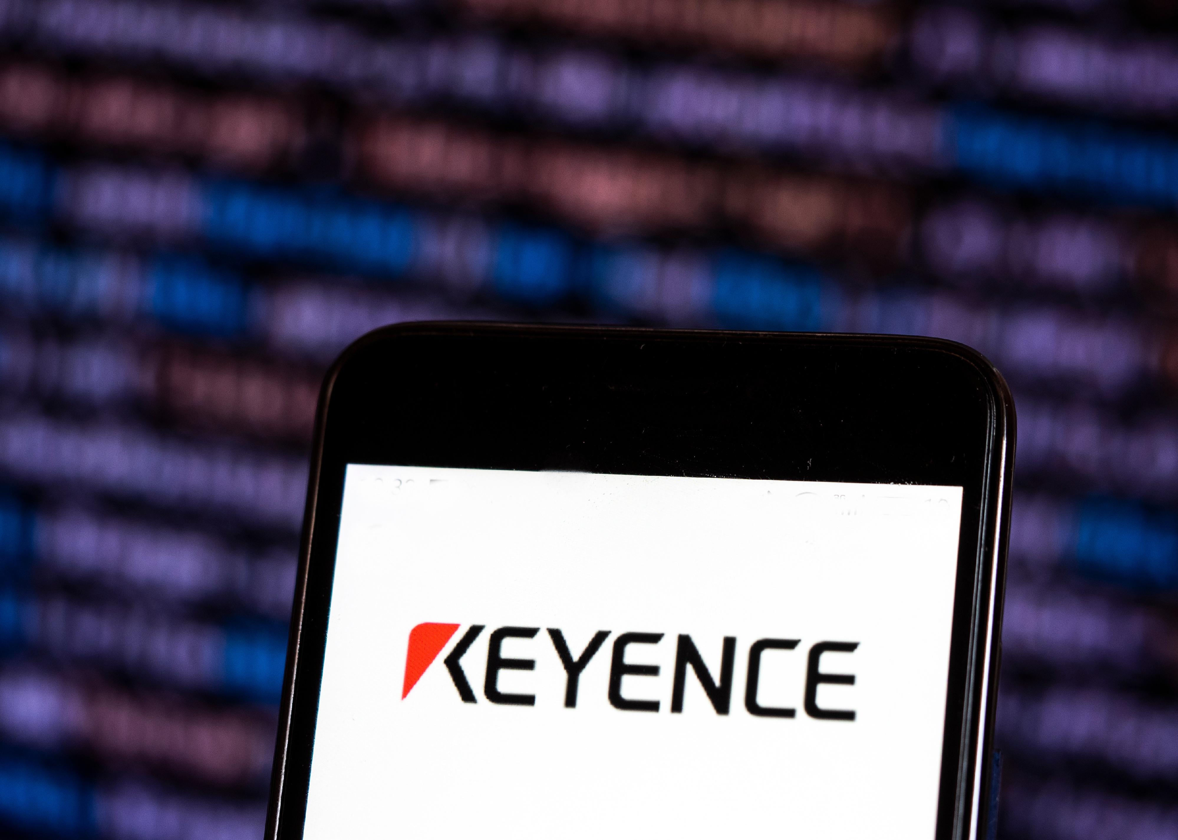 The Keyence logo on the screen of a smartphone. 
